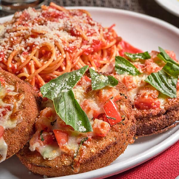 Closeup of Bertucci's Eggplant Parmesan on a plate topped with fresh basil and parmesan
