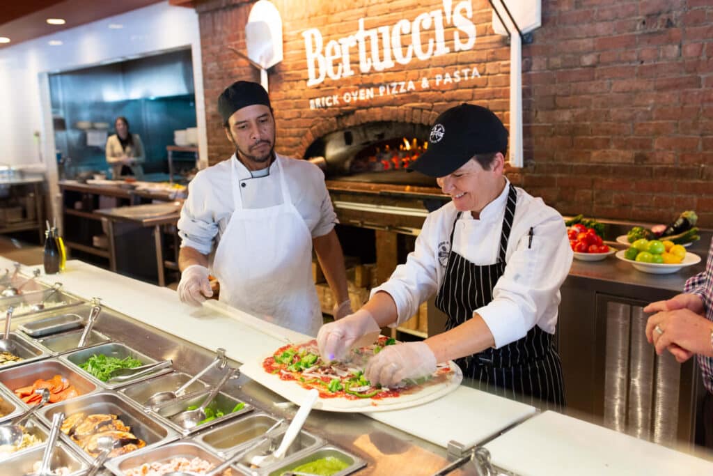 Careers at Bertucci's with an employee putting toppings on a pizza