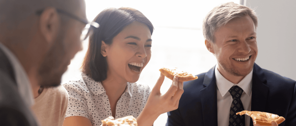 A corporate event at Bertucci's with people smiling and eating slices of pizza
